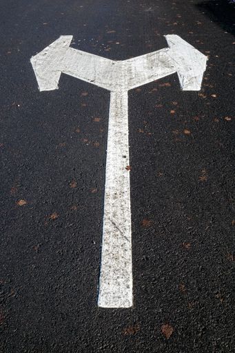 A vertical shot of a white directional arrow in a parking lot