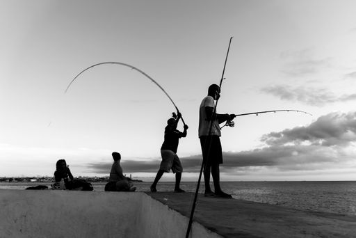 Silhouette of fishermen with their fishing poles on the rocks in search of fish. Salvador, Brazil