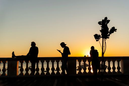 Silhouette of groups of people enjoying the beautiful sunset in Salvador at Porto da Barra beach. Well known and sought after tourist site.
