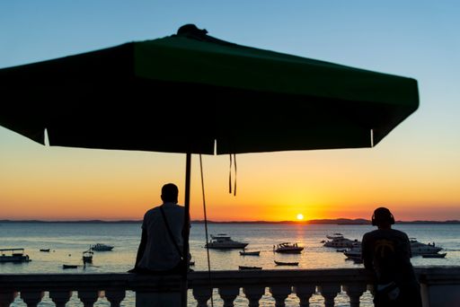 Silhouette of groups of people enjoying the beautiful sunset in Salvador at Porto da Barra beach. Well known and sought after tourist site.