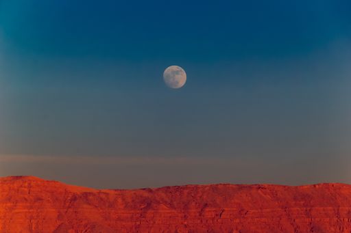 A view of mountains and the moon in the sky over them in Egypt
