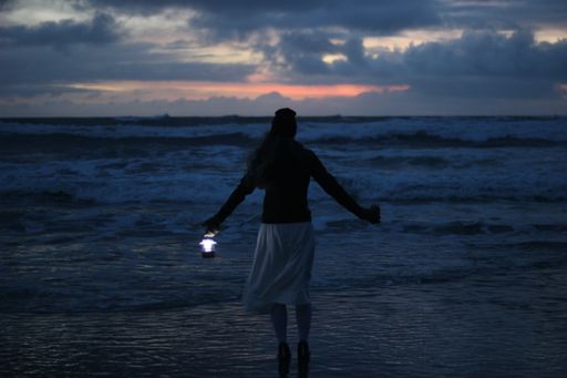 A woman standing on the beach as waves crash in front of her