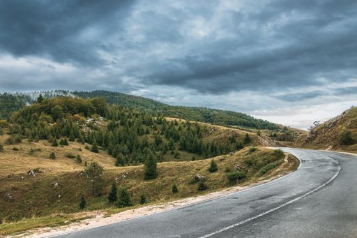 A mesmerizing view of a road asphalt way with cliffs on the side under a hazy gray sky