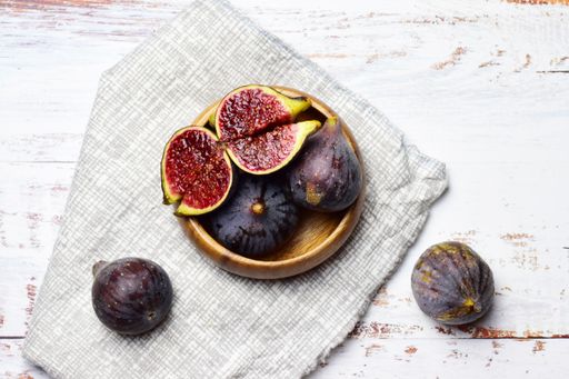 A top view of the yummy whole and halved figs on the checkered fabric and grunge wooden surface