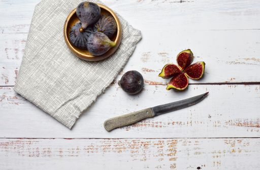 Yummy figs and kitchen knife on the checkered fabric on the wooden table
