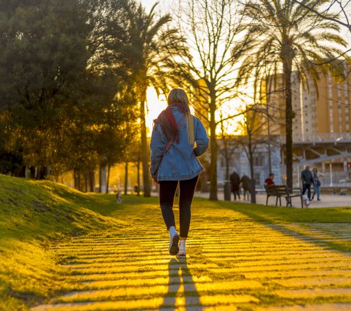 A young female walking through a park during the golden hour in Bilbao in Spain