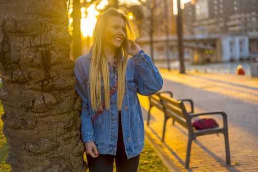 An attractive smiling female leaning on a tree in a park during the golden hour in Bilbao in Spain