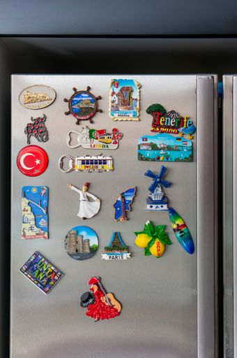 A vertical closeup shot of magnetic gift souvenirs from different countries attached to the fridge