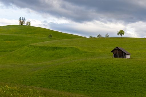 A breathtaking shot of a tiny house in a huge landscape under the cloudy skies