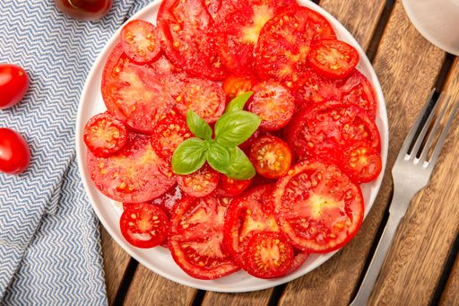 Top view of a plate of tasty fresh tomato salad with basil leaves Still life