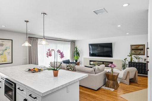 Contemporary living room with mounted TV, built-in fireplace, neutral tones, and bright natural light through sheer curtains