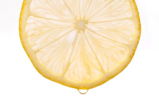 Close-up of a fresh lemon slice with a drop of juice against a white background.