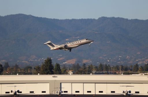 Bombardier Challenger 300 takes off from SJC with Santa Cruz mountains in the background.