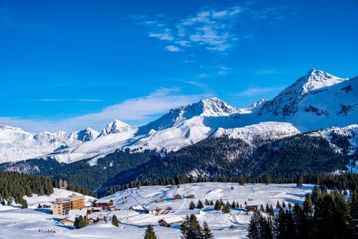 A winter view of snowy mountains and forest with blue sky in the background, Arosa, Switzerland