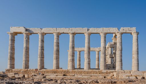 An ancient Temple of Poseidon in Greece with clear blue sky and sunlit columns showcasing classical architecture.