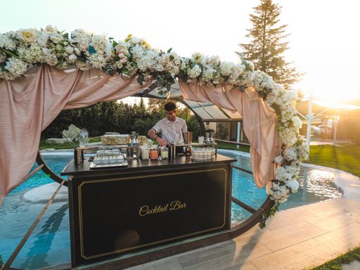 A young Caucasian barman making a refreshing cocktail outdoors by the pool at an event