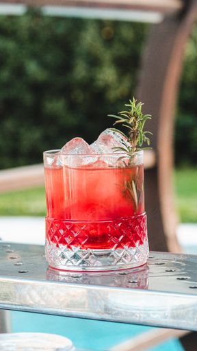 A vertical closeup shot of a glass of refreshing cocktail with ice cubes on a bar stand