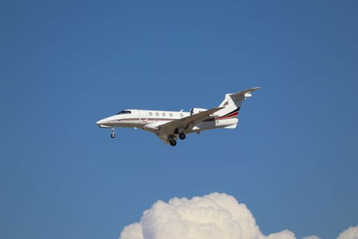 A private jet soaring in the sky with clouds and a clear blue backdrop