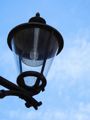 A vertical closeup shot of a street lamp against a cloudy sky