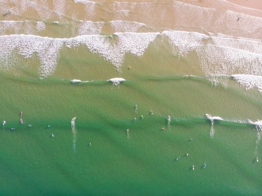 The Aerial view of people surfing in the waters of  beaches of San Vicente de la Barquera, Cantabria