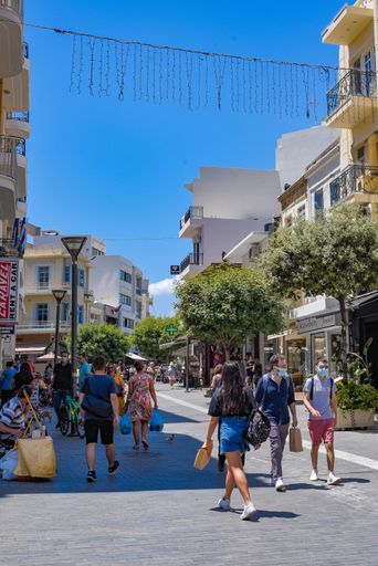 A vertical shot of tourists on the streets with white residential buildings in Heraklion, Greece