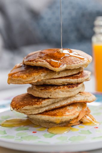 A closeup of a stack of pancakes with dripping maple syrup