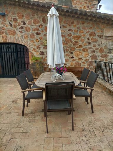 A wooden table with several chairs in the terrace of an old-styled restaurant