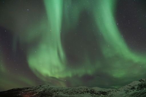 A mesmerizing view of the Aurora Borealis over the mountain in Kvaloya, Arctic region in Norway