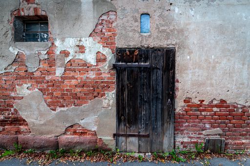 An old building facade with a small window and a wooden door
