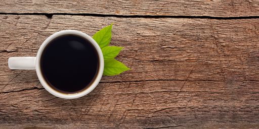 A top view of a cup of coffee on a wooden table with copy space