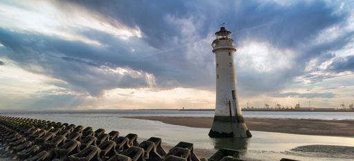 The lighthouse on New Brighton beach with seawater in the background against a cloudy sky