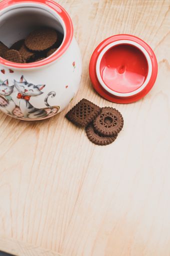 cocoa and chocolate cookies in a finely decorated stoneware jar on a rough wood tabletop with text space