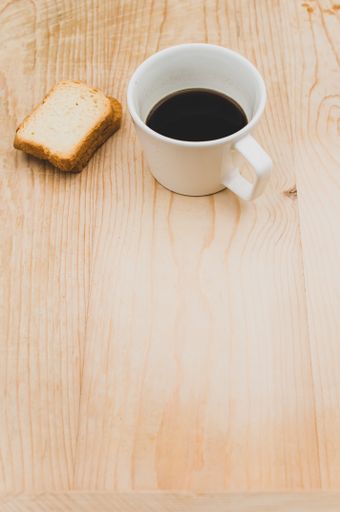 black coffee in a white mug and rusks on a rough wooden background with space for text