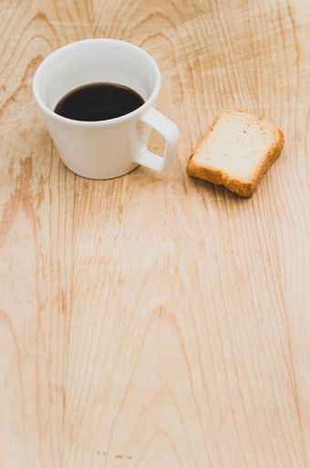black coffee in a white mug and rusks on a rough wooden background with space for text