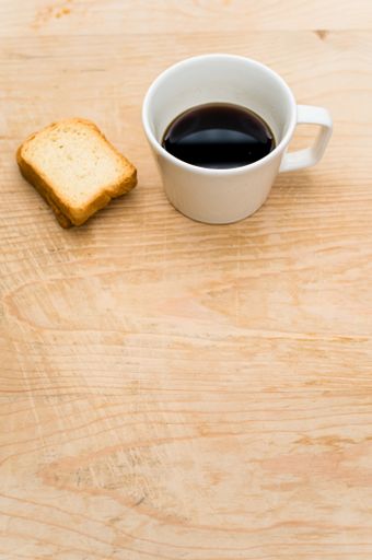 black coffee in a white mug and rusks on a rough wooden background with space for text