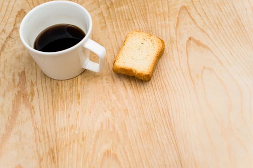 black coffee in a white mug and rusks on a rough wooden background with space for text