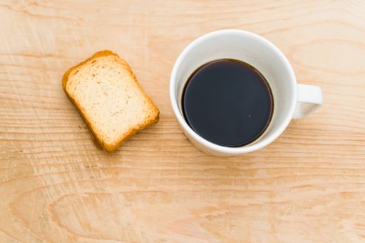 black coffee in a white mug and rusks on a rough wooden background with space for text