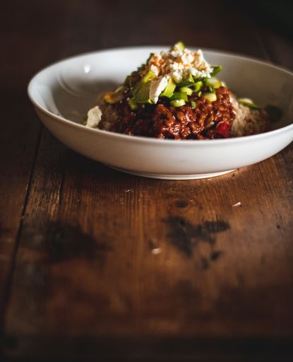 A vertical shot of a tasty dish with rice and sauce in a white plate on a wooden table