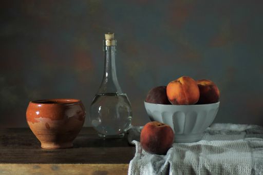 A Closeup of a bowl ofpeach and drinks  on a wooden table on a dark background