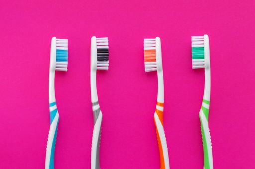 A Multicolored toothbrushes on a pink background