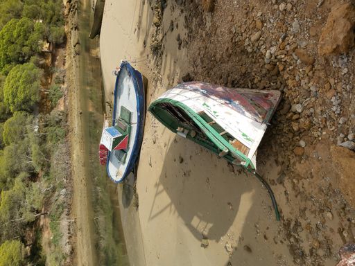 A pair of boats abandoned on a lake shore
