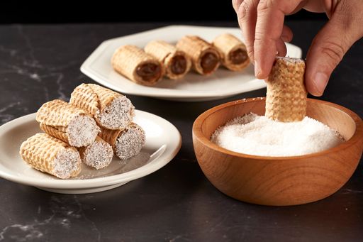 A hand covering with grated coconut cubanitos with dulce de leche.