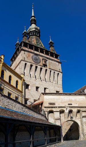 A vertical shot of the clock tower in the fortress of Sighisoara under a blue sky in Romania