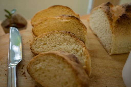 A selective focus shot of sliced loaf bread beside a bread knife on a wooden table