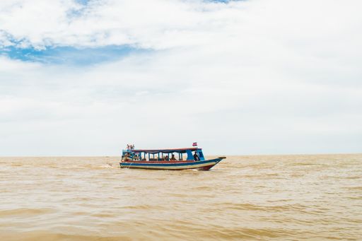 Colorful boat travelling on the brown muddy water of Tonle Sap Lake and river, near the fishing village of Kampong Phluk, Siem Reap, Cambodia, Asia.