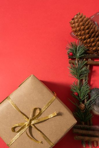 A wrapped Christmas gift with golden bow on red background