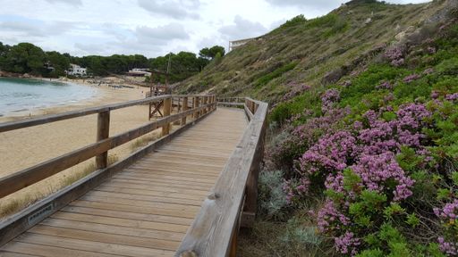 A wooden walkway on the beach of Minorca under a cloudy sky in the Balearic Islands, Spain