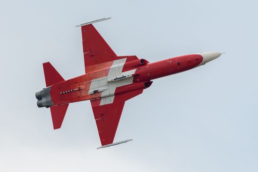 A red jet airplane of the Swiss Airforce performing stunts during an airshow in Belgium