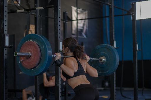 A young sporty woman in a protective mask exercising with a barbell in the gym
