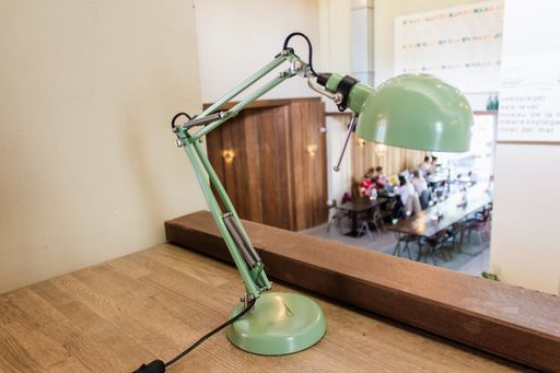 A close shot of an old-style desk lamp on a wooden table with a blurred background